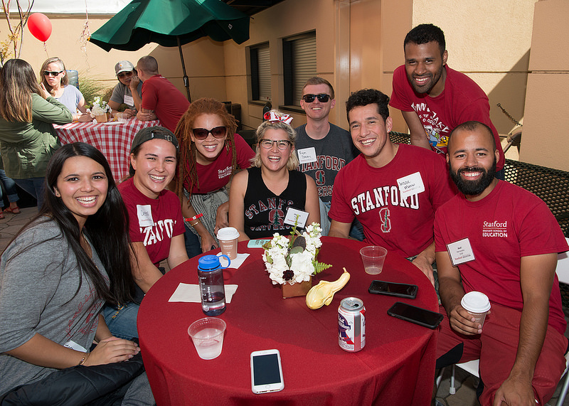 Photo of a group of Stanford alumni sitting at a round table posing for the camera.