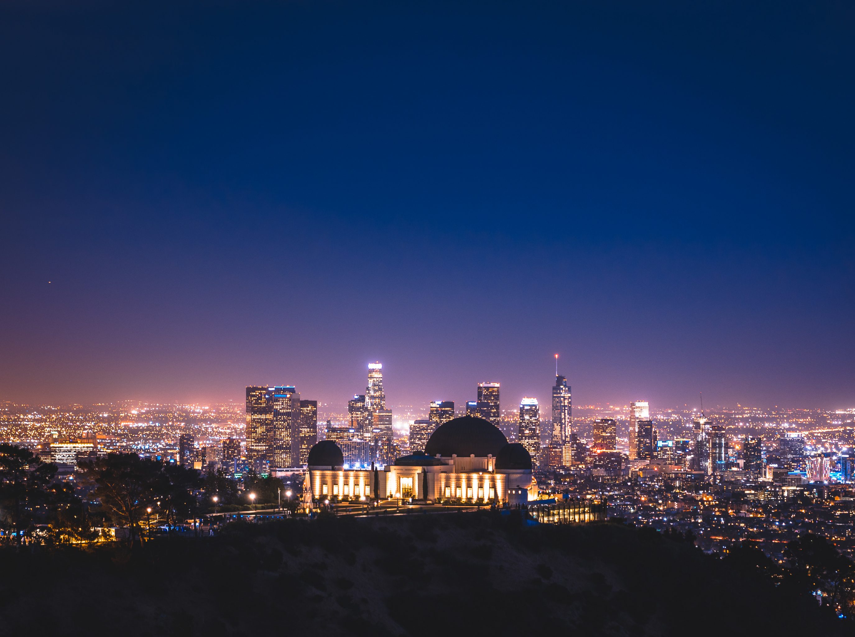 This is a nighttime picture of the Los Angeles skyline with the Griffith Observatory in the foreground. 